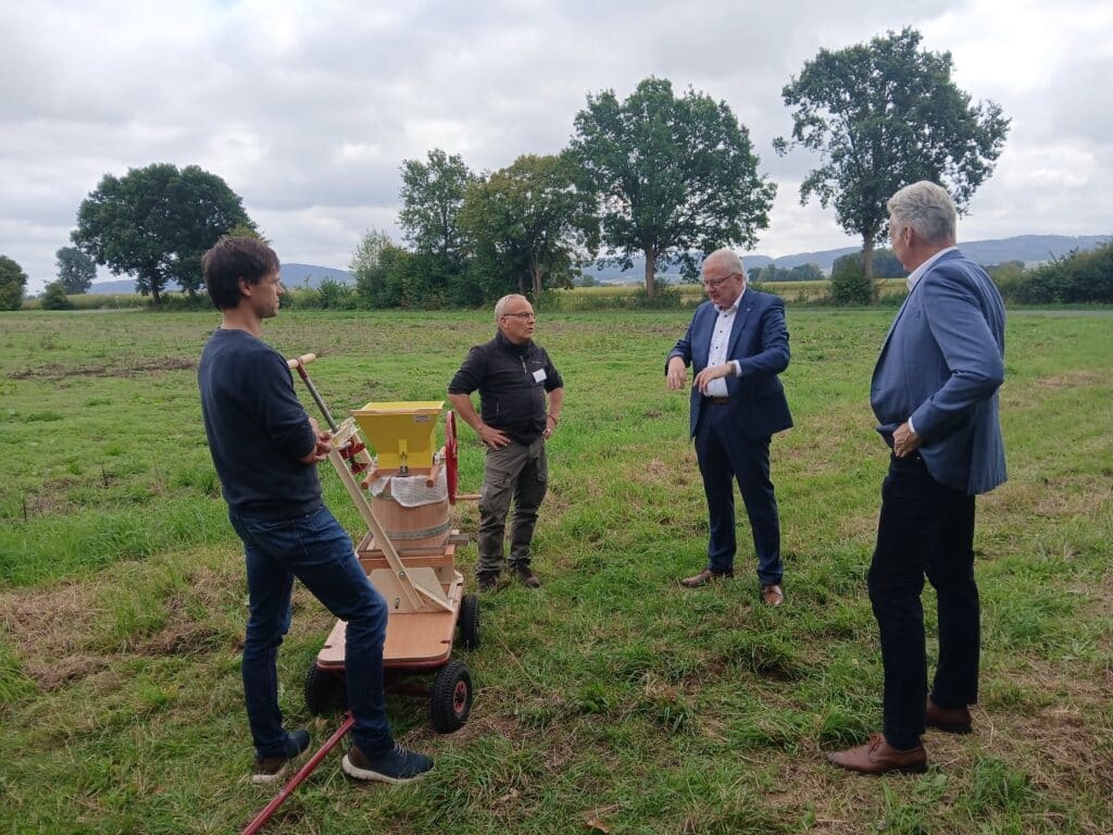 Vertreter der Volksbank und der Biologischen Station an der Apfelpresse auf einer Wiese